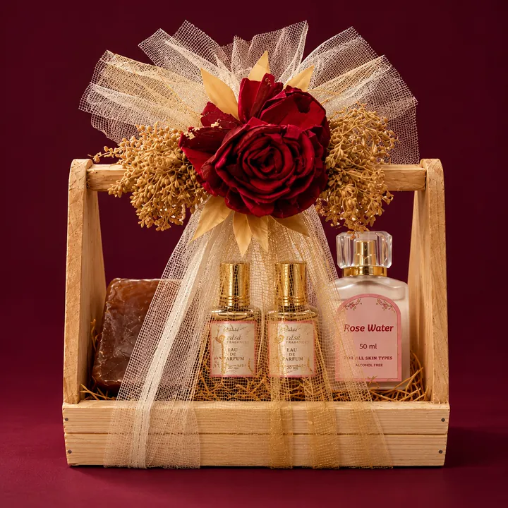 A wooden tray hamper tied with gold tulle and red roses, holding two VASA bottles and a bottle of rose water